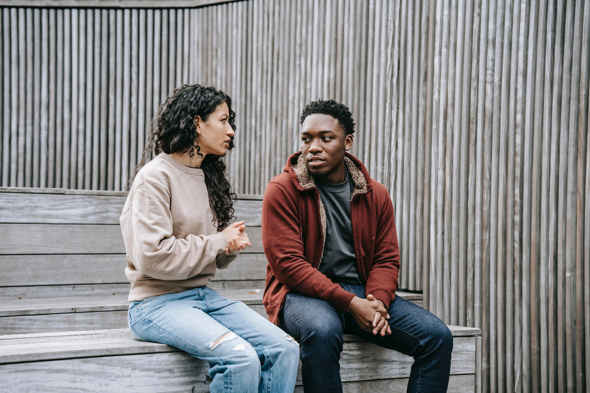 A man and a woman sit together having a serious discussion. They are looking directly at one another, showing that there is intent listening happening.